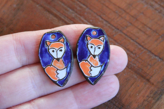 A pair of ceramic earring dangles with foxes