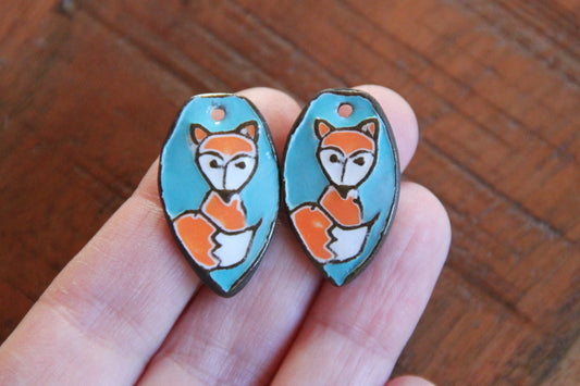 A pair of ceramic earring dangles with foxes