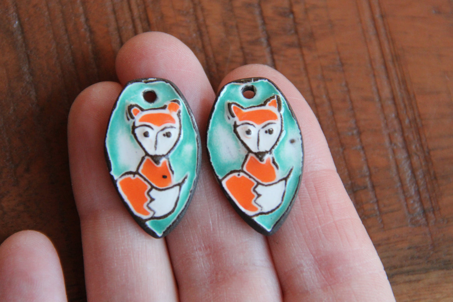 A pair of ceramic earring dangles with foxes