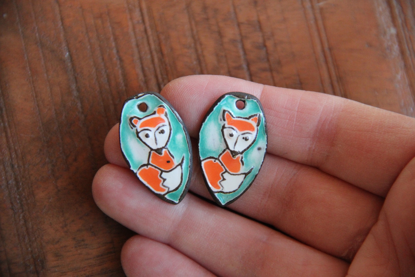 A pair of ceramic earring dangles with foxes